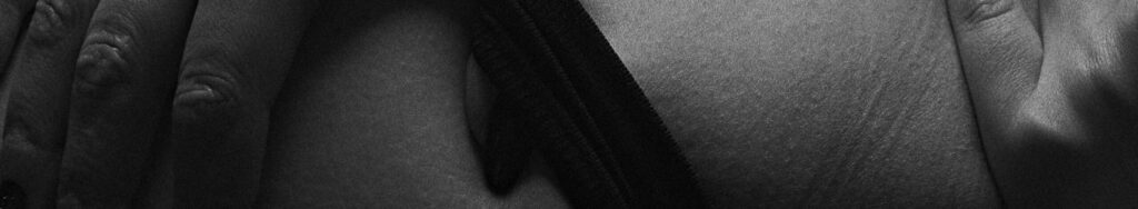 A sensual black and white close-up of hands touching skin, conveying intimacy and connection.